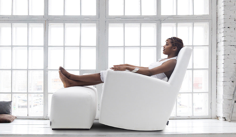 Tummaihoinen tyttö istuu valkoisella Swing-keinutuolilla jossa rahi, takana iso valkoinen ikkuna.