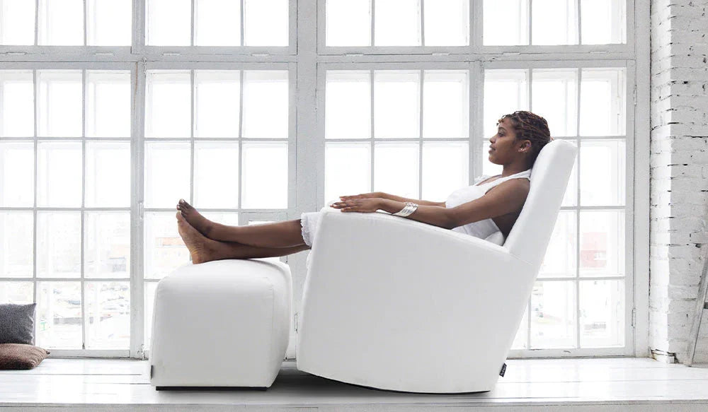 Tummaihoinen tyttö istuu valkoisella Swing-keinutuolilla jossa rahi, takana iso valkoinen ikkuna. 