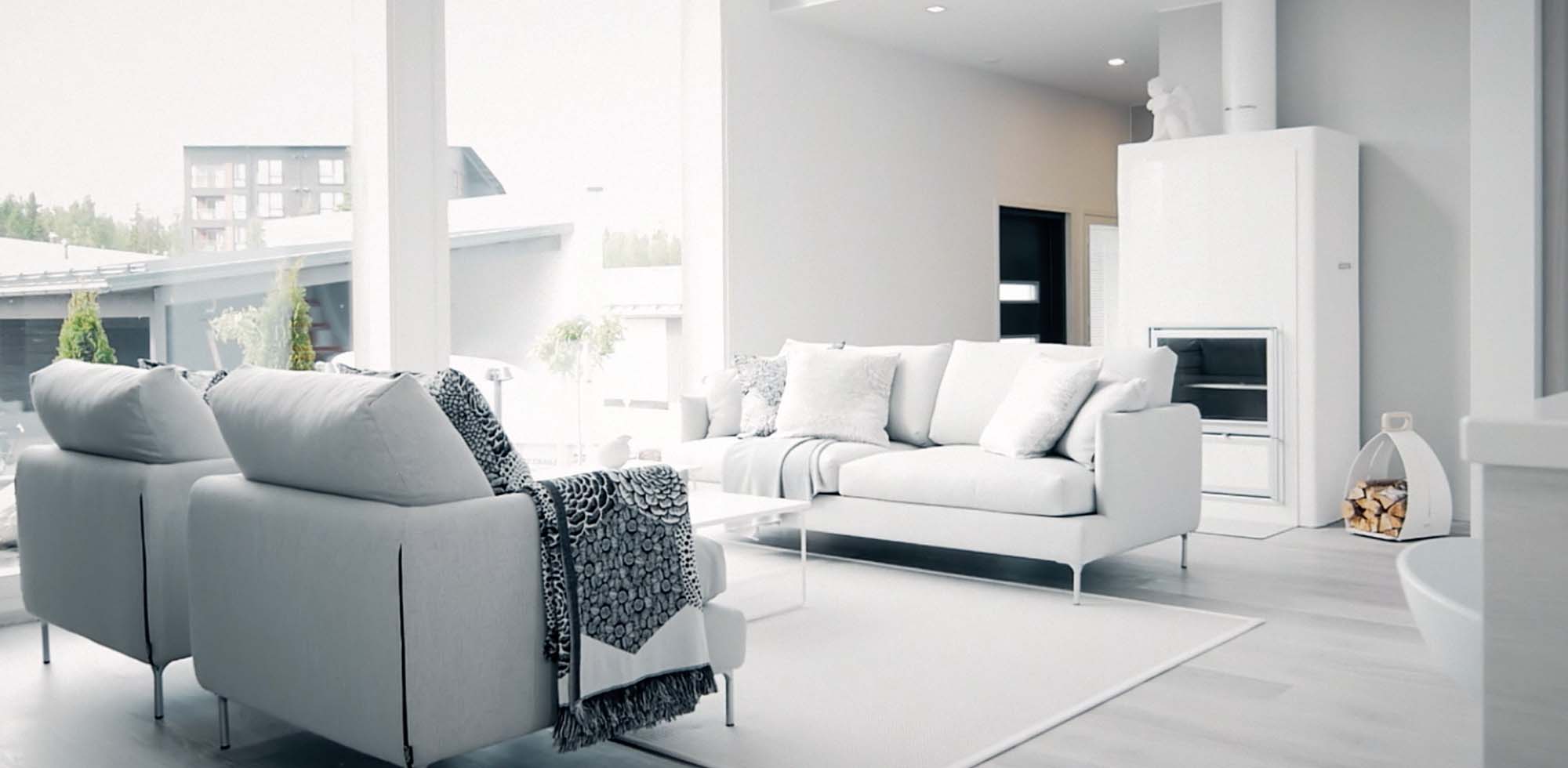 HT Collectionin Como sohva ja kaksi nojatuolia olohuoneessa jossa isot ikkunat ja valkoinen takka. 