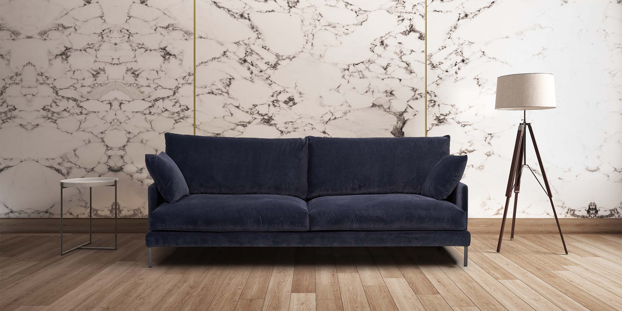 Sininen HT Collectionin Luca-sohva vieressä sohvapöytä ja lamppu, marmorikuvioisen seinän edessä