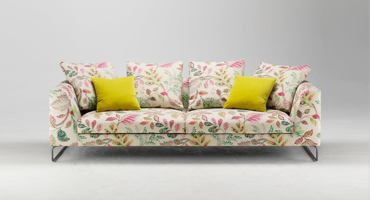 HT Collectionin Coco-sohva kangasverhoilulla, jossa vaalealla pohjalla punaisia ja vihreitä lehtikuvioita.