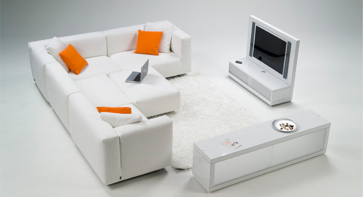 HT Collectionin Base kulmasohvaryhmä ja rahi valkoisella kankaalla sekä samaan sarjaan kuuluneet tv-taso sekä laatikosto.