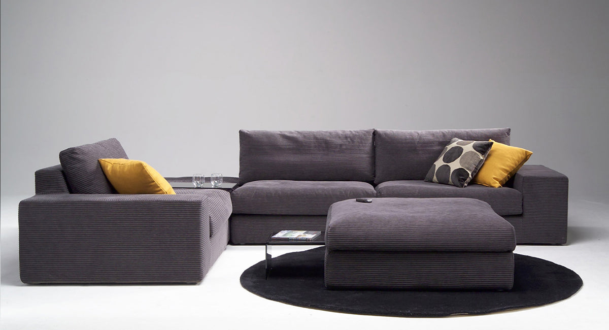 HT Collectionin M-sohvan isompi kokoonpano jossa kaksi kulmapalaa ja kaksi rahia harmaanruskealla samettisella kankaalla sekä piilopöytä